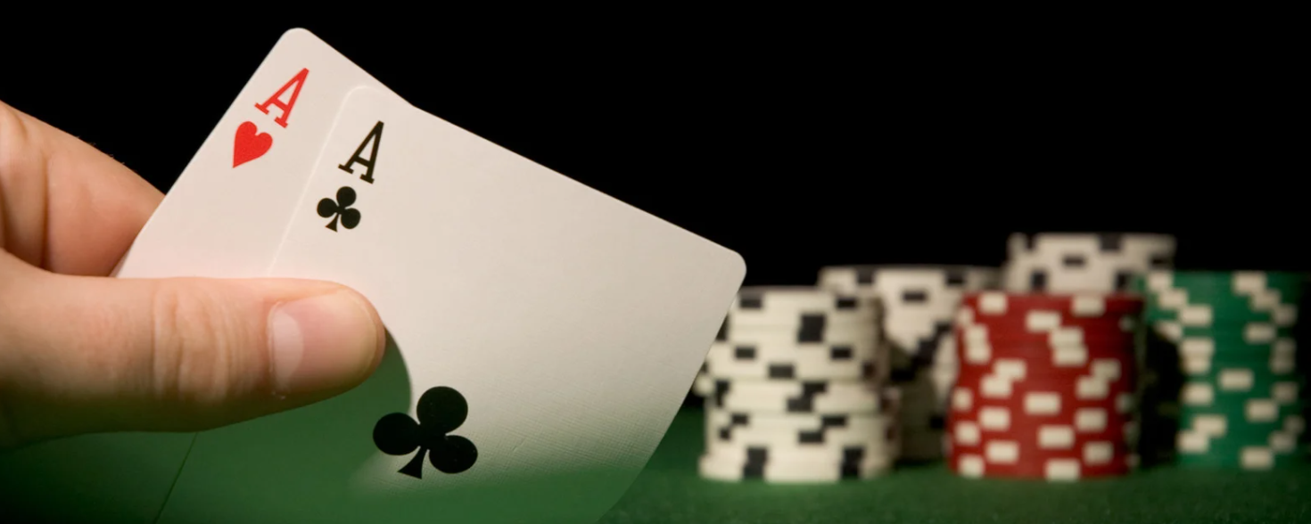Poker player holding a pair of aces with stacked poker chips during a cash game promotion